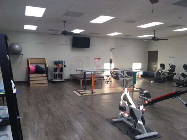 Open physical therapy treatment room with exercise equipment